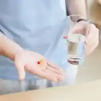 pictrure of a man holding cup of water and a pill